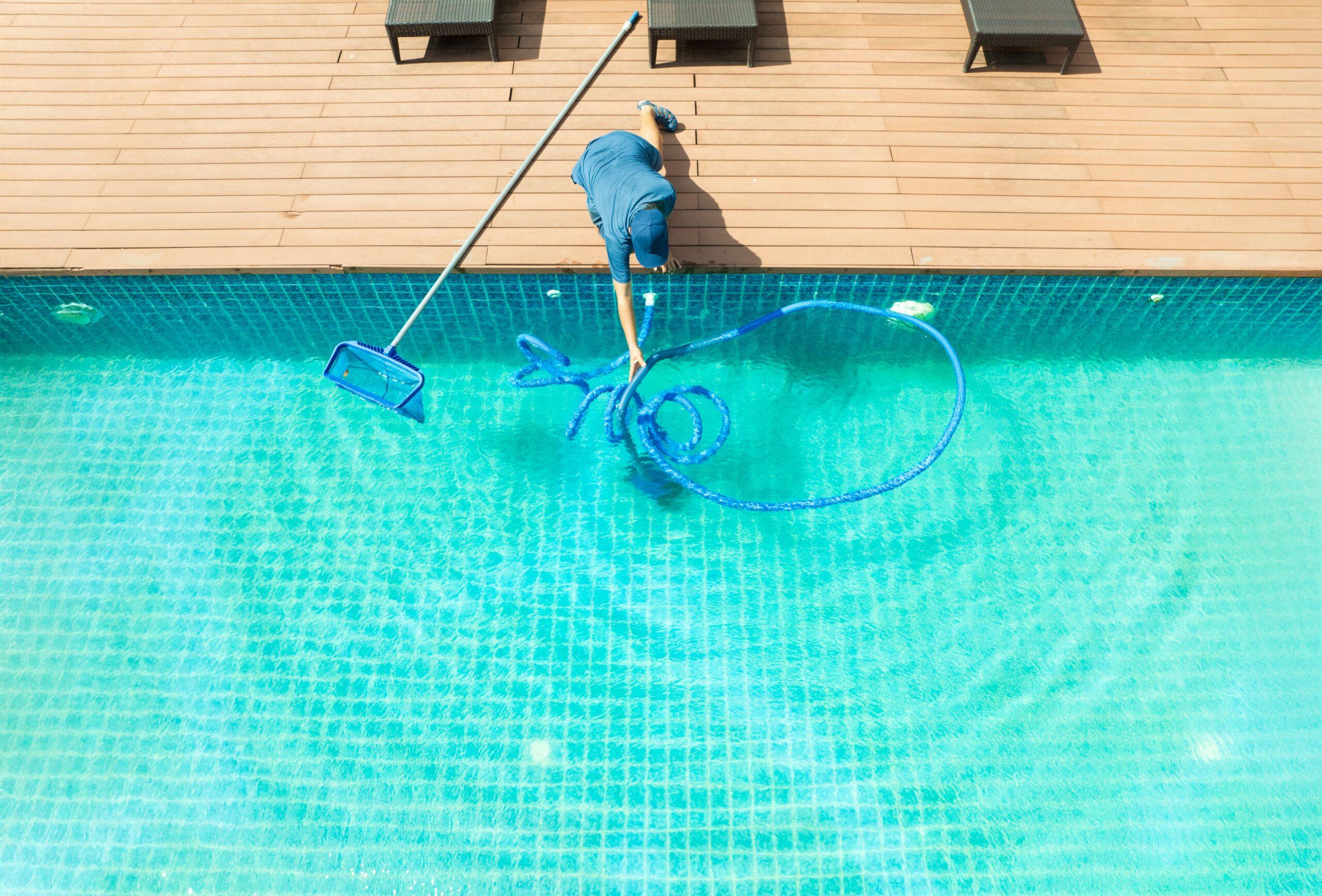Mann bei der Poolpflege mit Kescher und Saugschlauch
